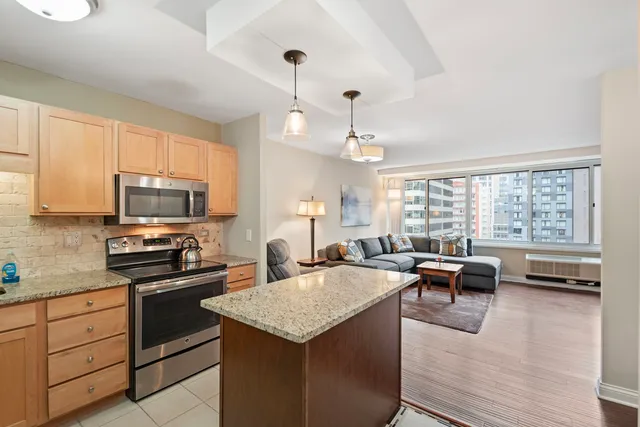 a kitchen with kitchen island a large counter top space and stainless steel appliances