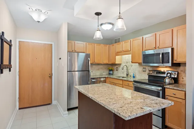 a kitchen with stainless steel appliances granite countertop a sink refrigerator stove and microwave