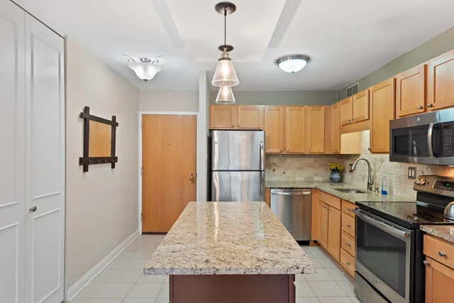 a kitchen with stainless steel appliances granite countertop a sink refrigerator stove and microwave