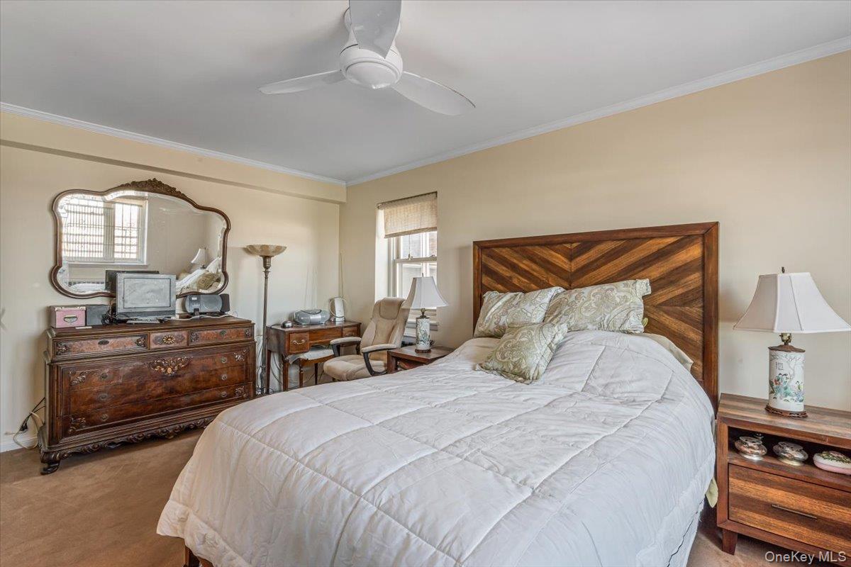 144-60 Gravett Road, Unit 6F Queens, NY 11367 - Photo 8 of 20 a bedroom with a bed a mirror on dresser and a chandelier