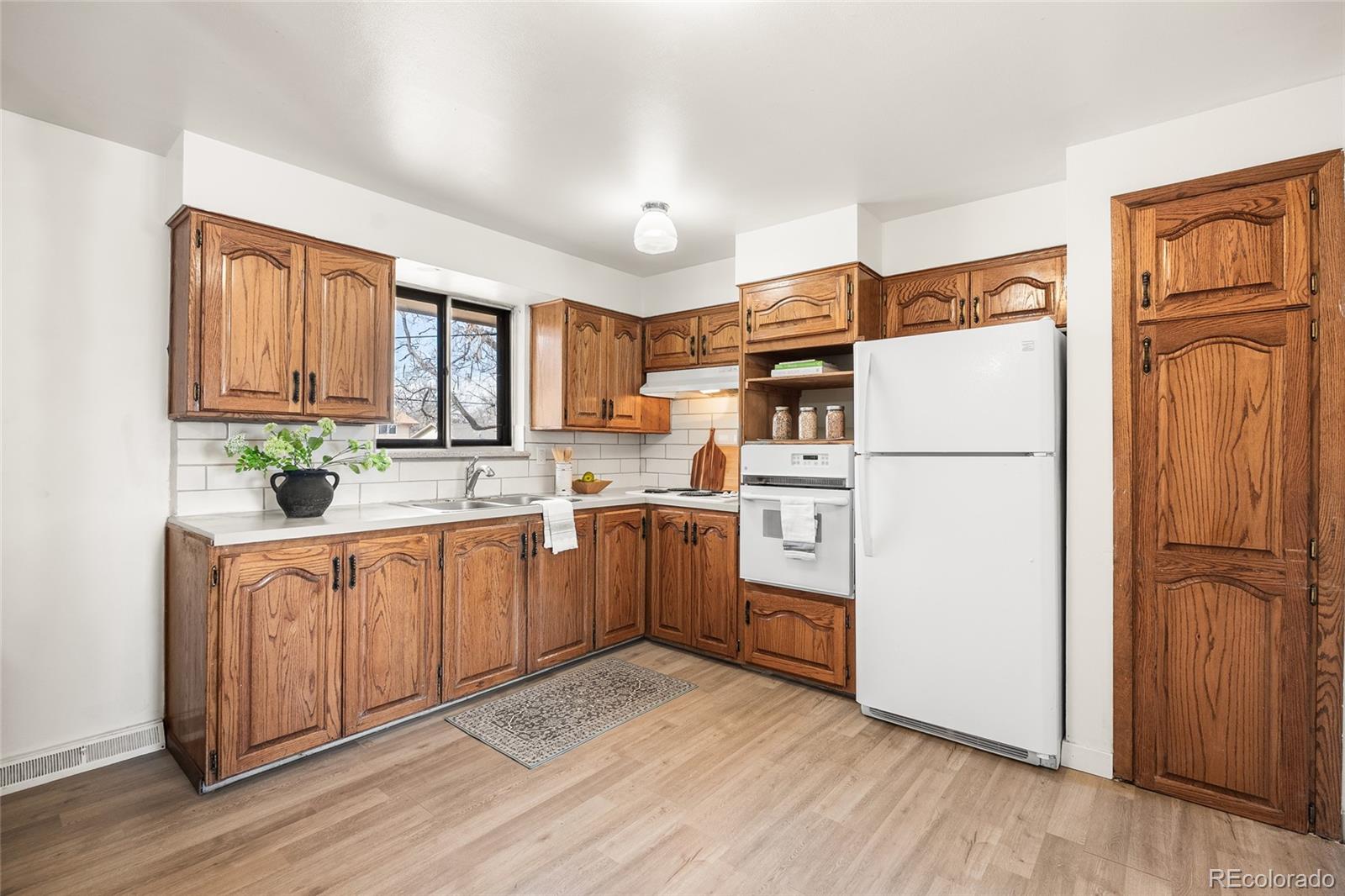 4585 Garland Street Wheat Ridge, CO 80033 - Photo 12 of 35 a kitchen with sink refrigerator and cabinets
