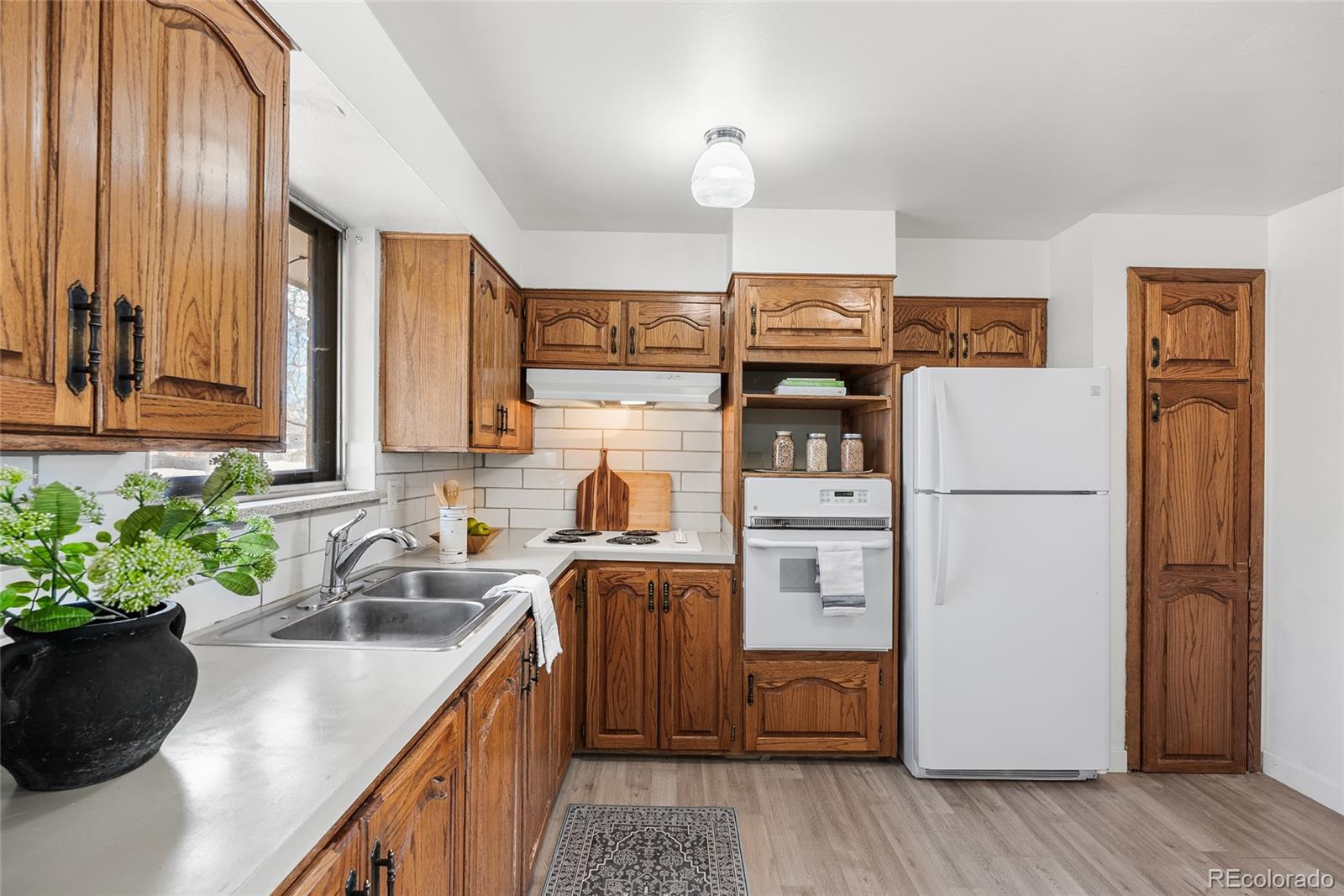 4585 Garland Street Wheat Ridge, CO 80033 - Photo 9 of 35 a kitchen with stainless steel appliances granite countertop a refrigerator a stove a sink dishwasher and microwave with wooden floor