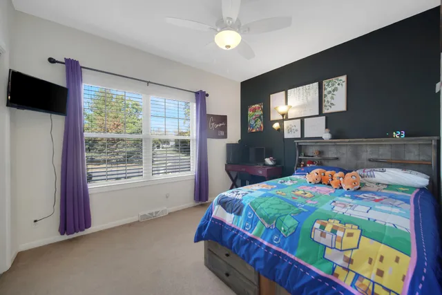 a bedroom with bed and a flat tv screen on dresser