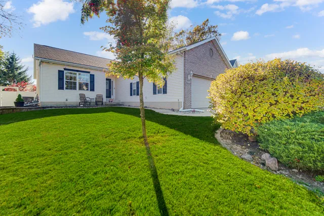 a view of a yard in front of a house with plants and large tree