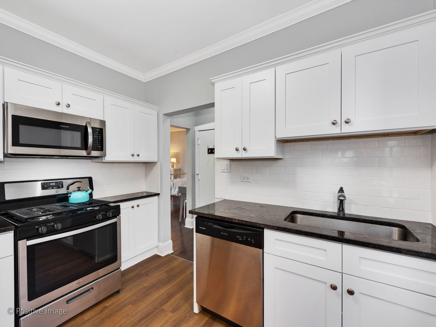 604 West Patterson Avenue, Unit 3A Chicago, IL 60613 - Photo 8 of 11 a kitchen with stainless steel appliances granite countertop white cabinets a sink a stove a microwave and wooden floors