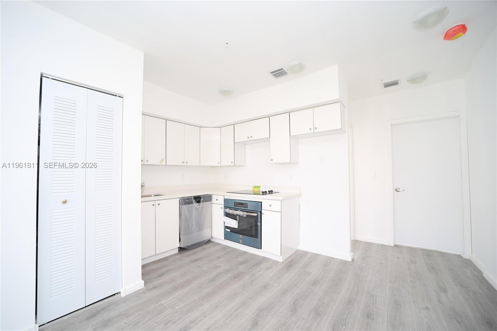 810 7th Street, Unit 104 Miami Beach, FL 33139 - Photo 3 of 11 a kitchen with cabinets wooden floor and stainless steel appliances