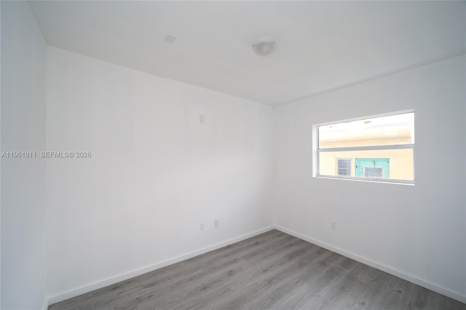 810 7th Street, Unit 104 Miami Beach, FL 33139 - Photo 10 of 11 a view of an empty room with wooden floor and a window