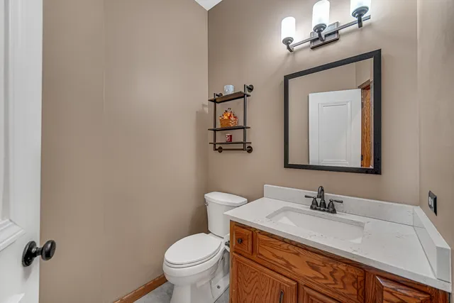 a bathroom with a granite countertop sink vanity mirror and toilet