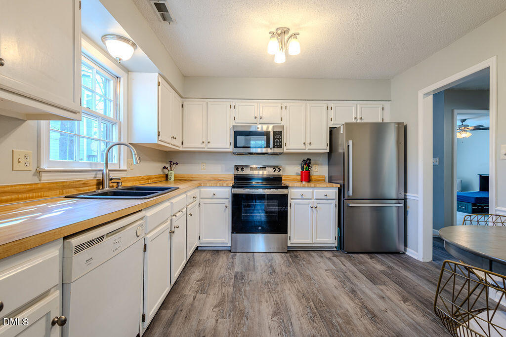 213 Bracken Court Raleigh, NC 27615 - Photo 4 of 20 a kitchen with a refrigerator cabinets and wooden floor