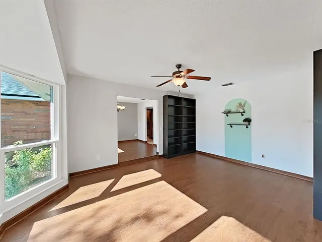a view of an empty room with a window and wooden floor