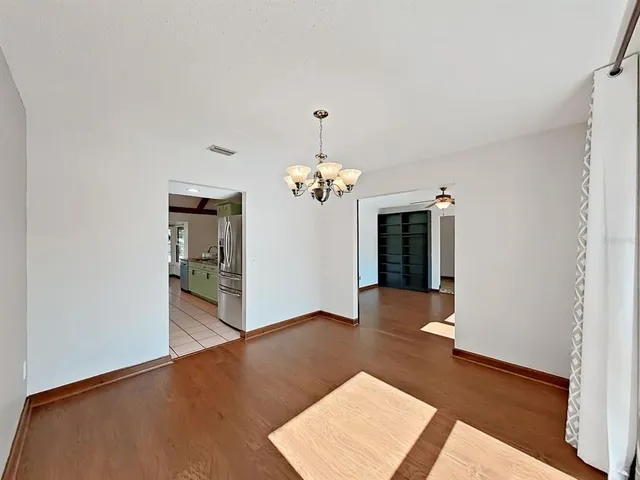 an empty room with wooden floor closet and windows