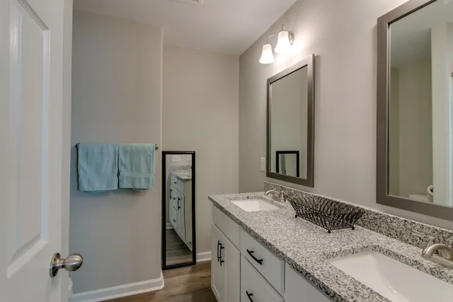a bathroom with a granite countertop double vanity sink and mirror