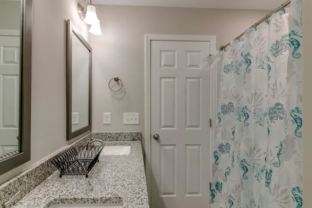a bathroom with a granite countertop shower and a mirror