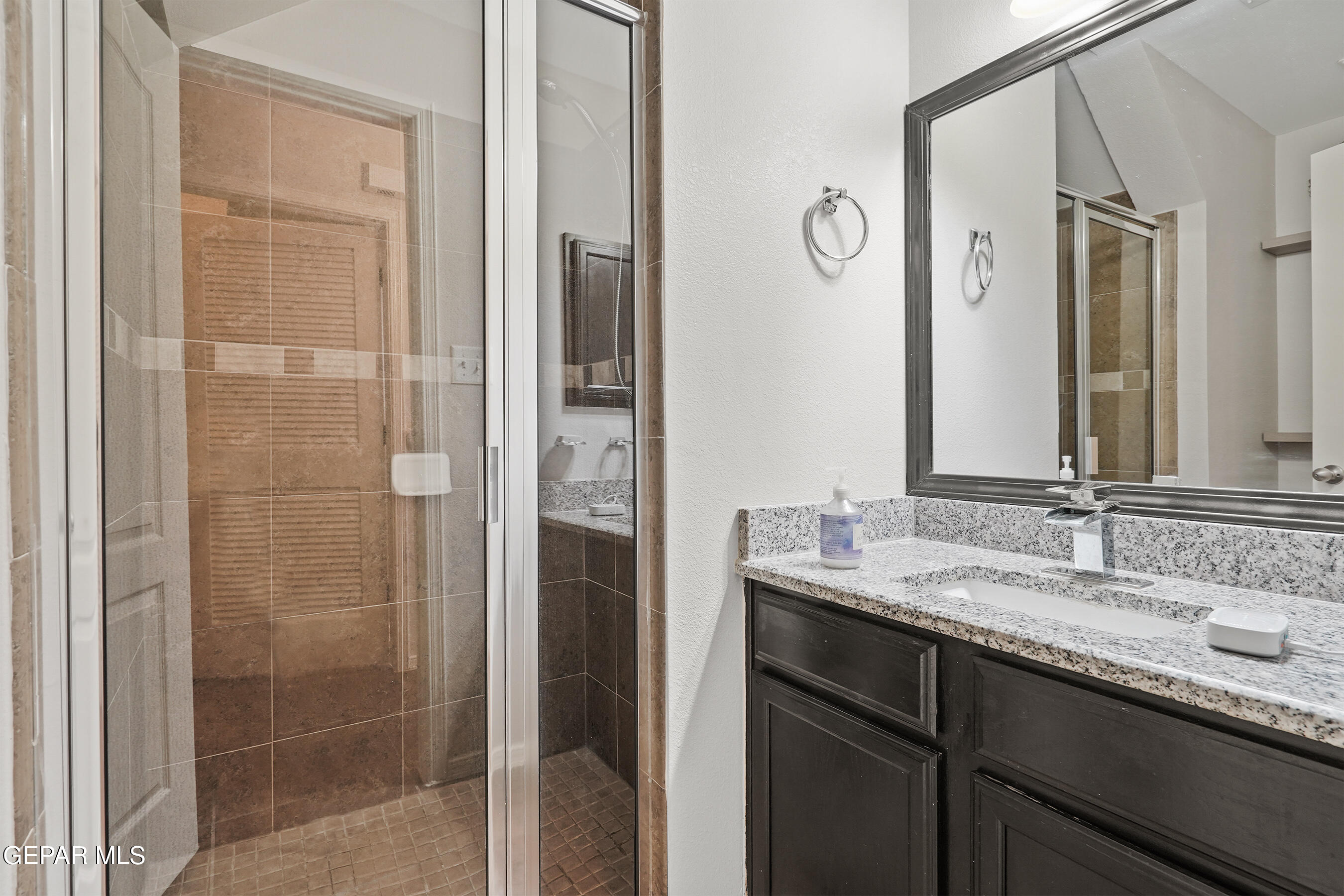 11265 Cattle Ranch Street El Paso, TX 79934 - Photo 15 of 44 a bathroom with a granite countertop sink a mirror and a shower