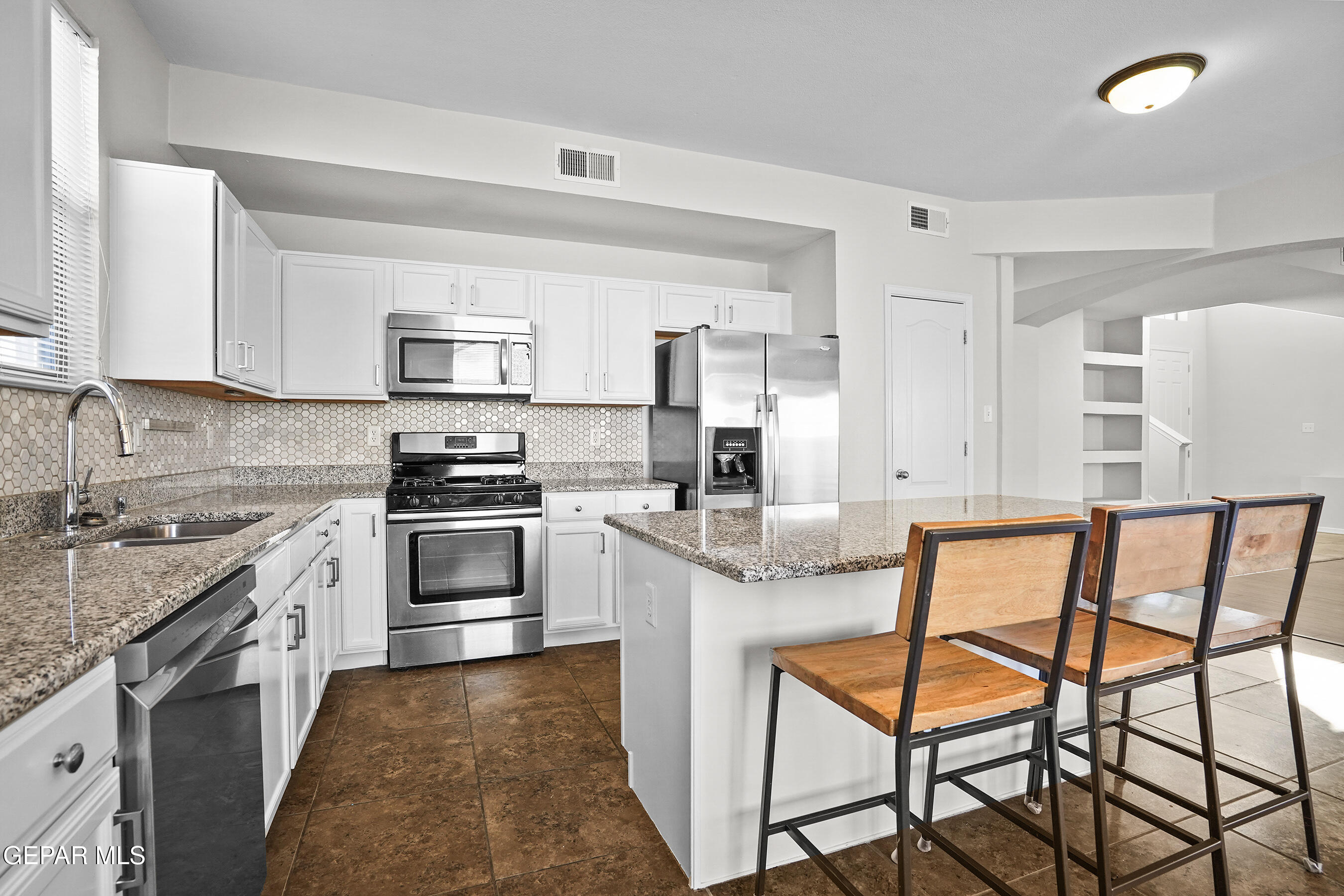 11265 Cattle Ranch Street El Paso, TX 79934 - Photo 3 of 44 a kitchen with stainless steel appliances granite countertop a stove top oven a sink a refrigerator and white cabinets