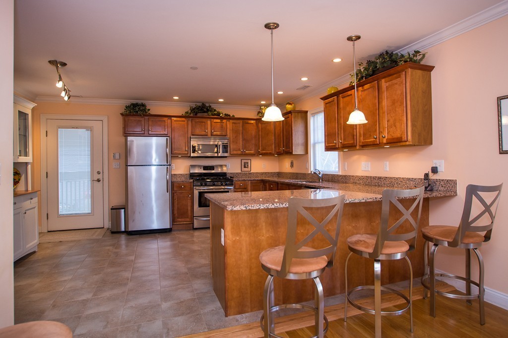 69 Parkton Road, Unit 1 Boston, MA 02130 - Photo 7 of 30 a kitchen with stainless steel appliances kitchen island granite countertop a refrigerator and a stove top oven