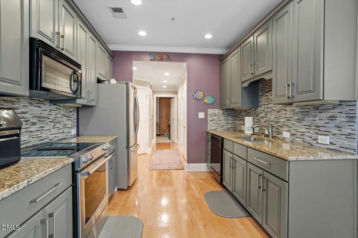 3700 Baron Cooper Pass, Unit 204 Raleigh, NC 27612 - Photo 15 of 39 a kitchen with stainless steel appliances granite countertop a refrigerator a stove top oven a sink and dishwasher
