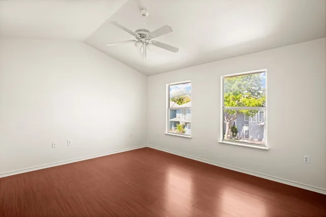 a view of an empty room with a window and wooden floor