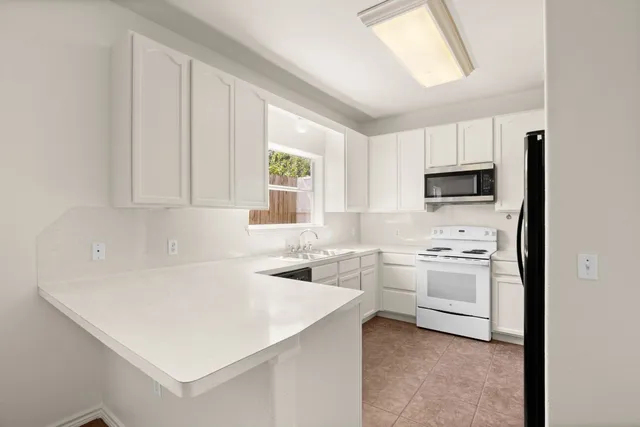 a kitchen with white cabinets and white appliances