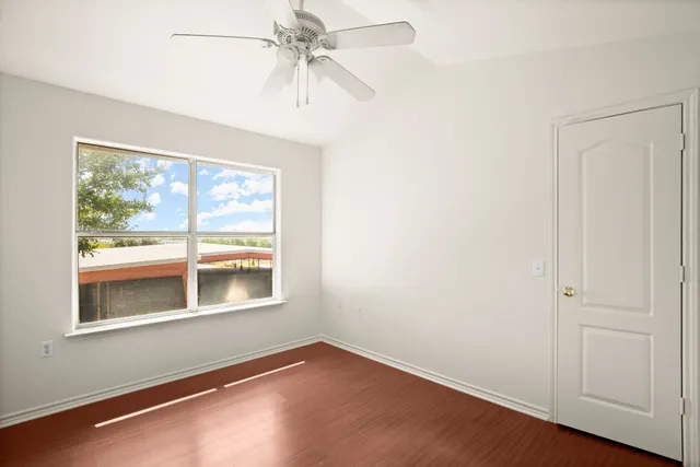 an empty room with a window and a ceiling fan