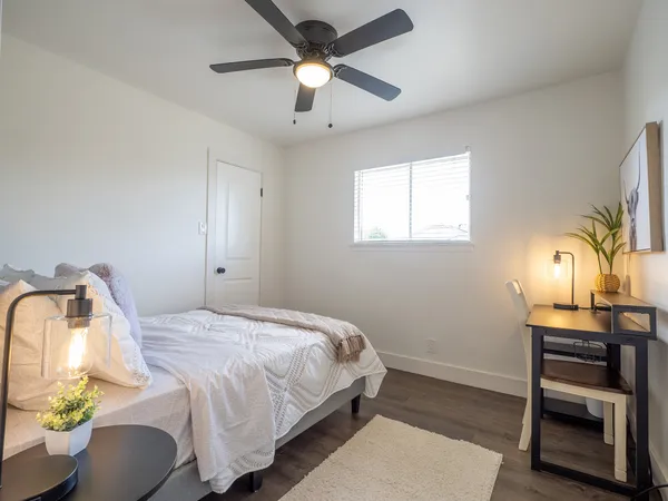 a bedroom with a bed a dresser and potted plants