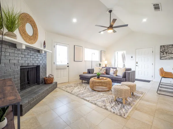 a living room with furniture a fireplace and a ceiling fan