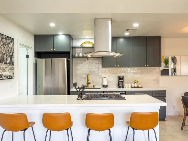 a kitchen with stainless steel appliances granite countertop a sink a stove a refrigerator a couch and chairs