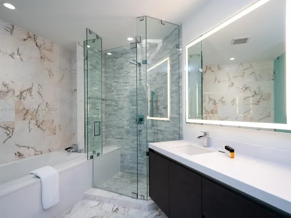 a bathroom with a bathtub shower sink mirror vanity and toilet