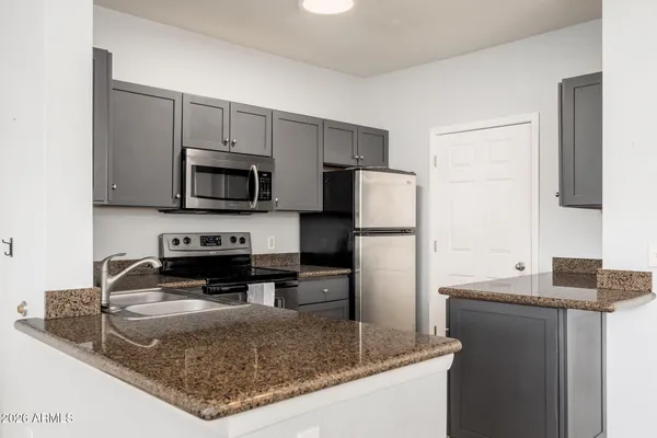 a kitchen with kitchen island granite countertop a sink stove and refrigerator