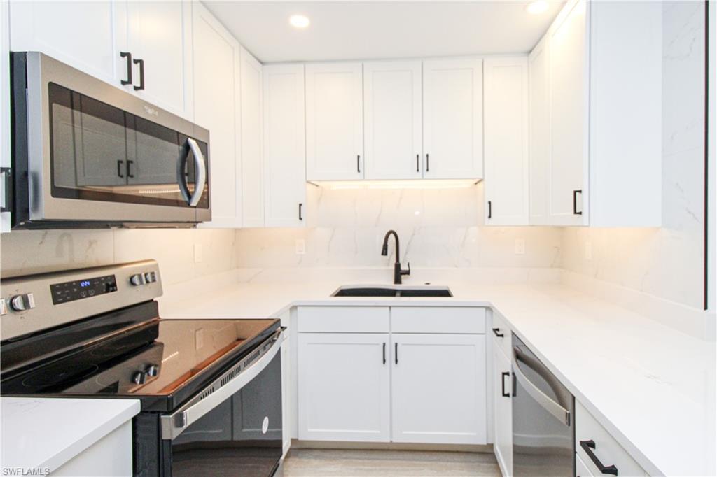 1435 Curlew Avenue, Unit 4 Naples, FL 34102 - Photo 1 of 26 a kitchen with white cabinets sink and stove