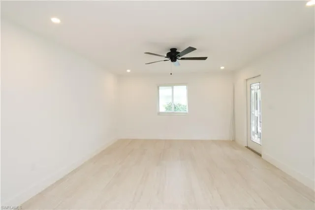 an empty room with windows and a ceiling fan