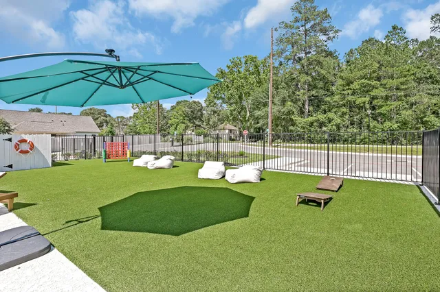 a view of pool with lawn chairs under an umbrella