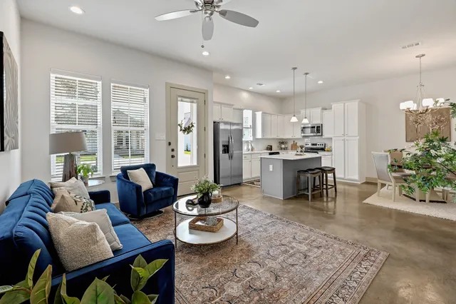 a living room with furniture kitchen view and a large window