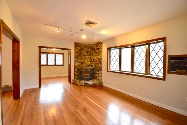 a view of an empty room with a window and wooden floor