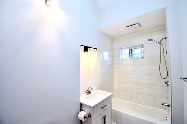 a bathroom with a tub shower sink and a mirror