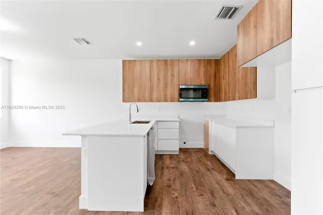 a kitchen with a sink a wooden floor and cabinets