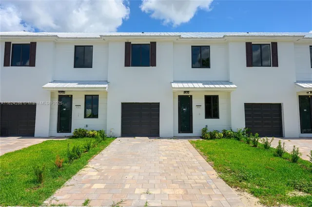 a front view of a house with a yard and potted plants