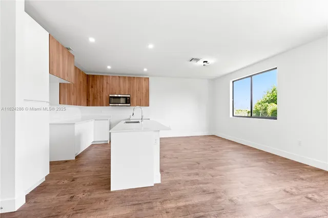 a view of a kitchen with a sink and dishwasher with wooden floor