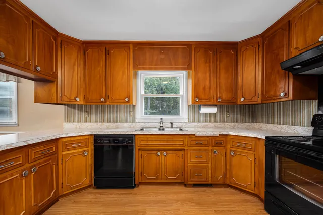 a kitchen with stainless steel appliances granite countertop wooden cabinets a refrigerator a stove a sink and dishwasher with wooden floor