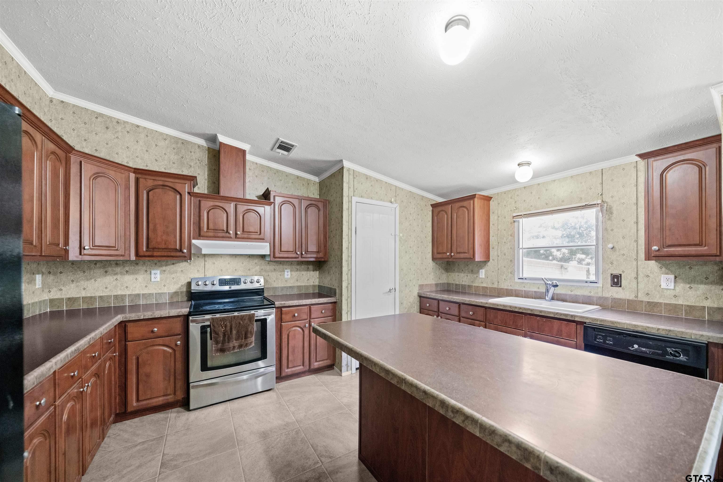 5611 Holiday Hills Road Tyler, TX 75708 - Photo 13 of 38 a kitchen with stainless steel appliances granite countertop a sink a stove top oven a counter space and cabinets