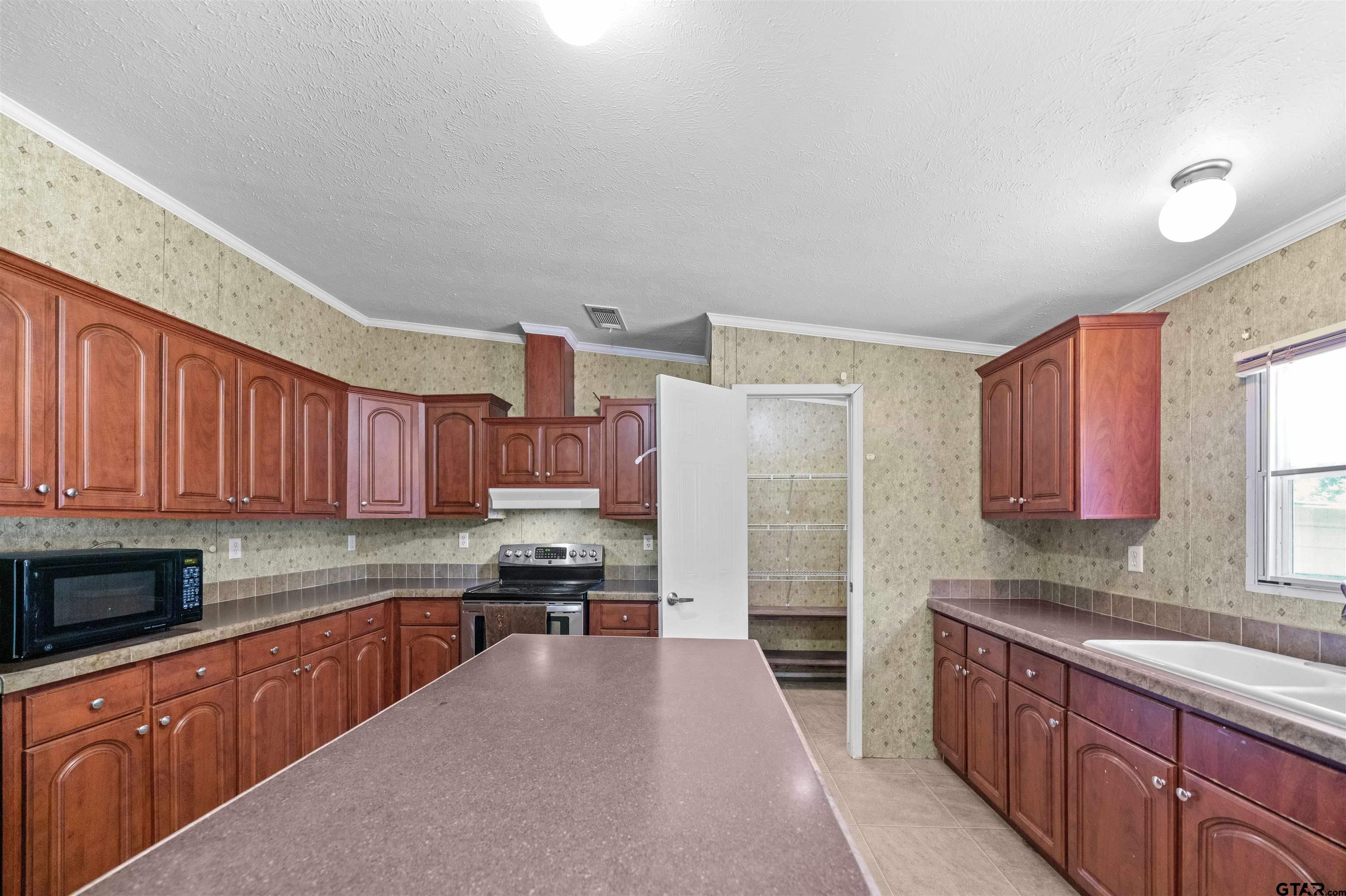 5611 Holiday Hills Road Tyler, TX 75708 - Photo 17 of 38 a kitchen with kitchen island granite countertop a stove top oven a sink dishwasher and a refrigerator with wooden cabinets