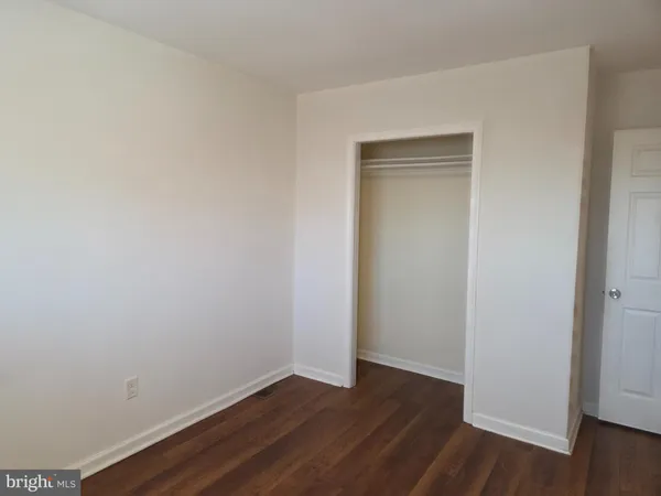 a view of an empty room with wooden floor and closet
