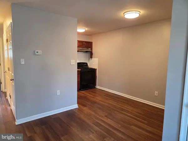 an empty room with wooden floor and a kitchen