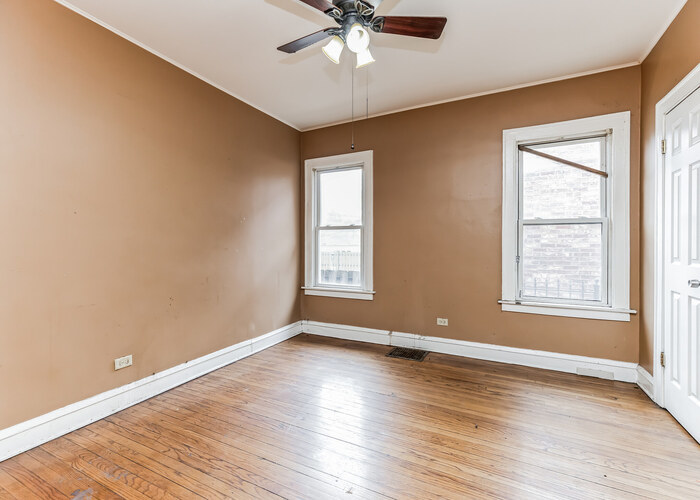 10805 South Normal Avenue Chicago, IL 60628 - Photo 15 of 26 an empty room with wooden floor chandelier fan and windows