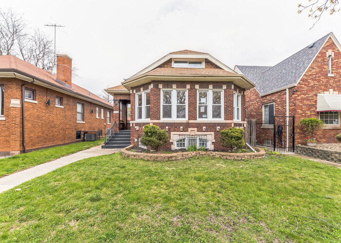 10805 South Normal Avenue Chicago, IL 60628 - Photo 2 of 26 a front view of a house with a yard table and chairs