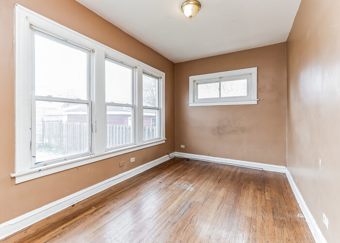 10805 South Normal Avenue Chicago, IL 60628 - Photo 5 of 26 an empty room with wooden floor and windows