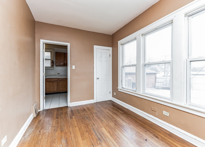 10805 South Normal Avenue Chicago, IL 60628 - Photo 6 of 26 a view of an empty room with a window and wooden floor