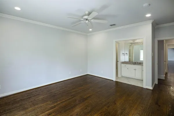 an empty room with wooden floor and a ceiling fan