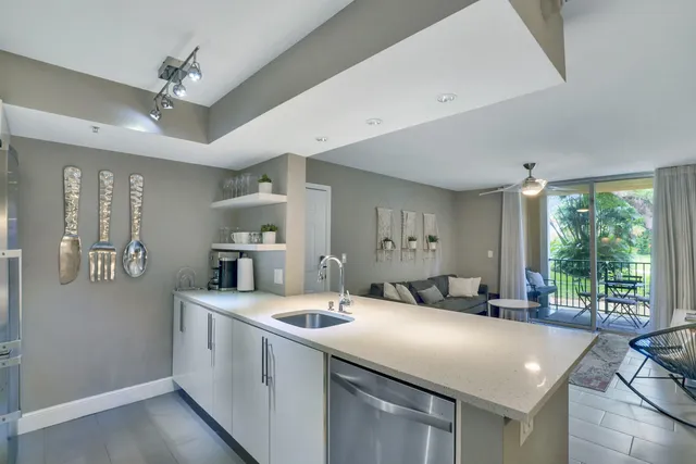 a kitchen with a sink a counter top space and living room view