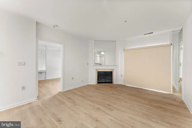 a view of empty room with wooden floor and fireplace